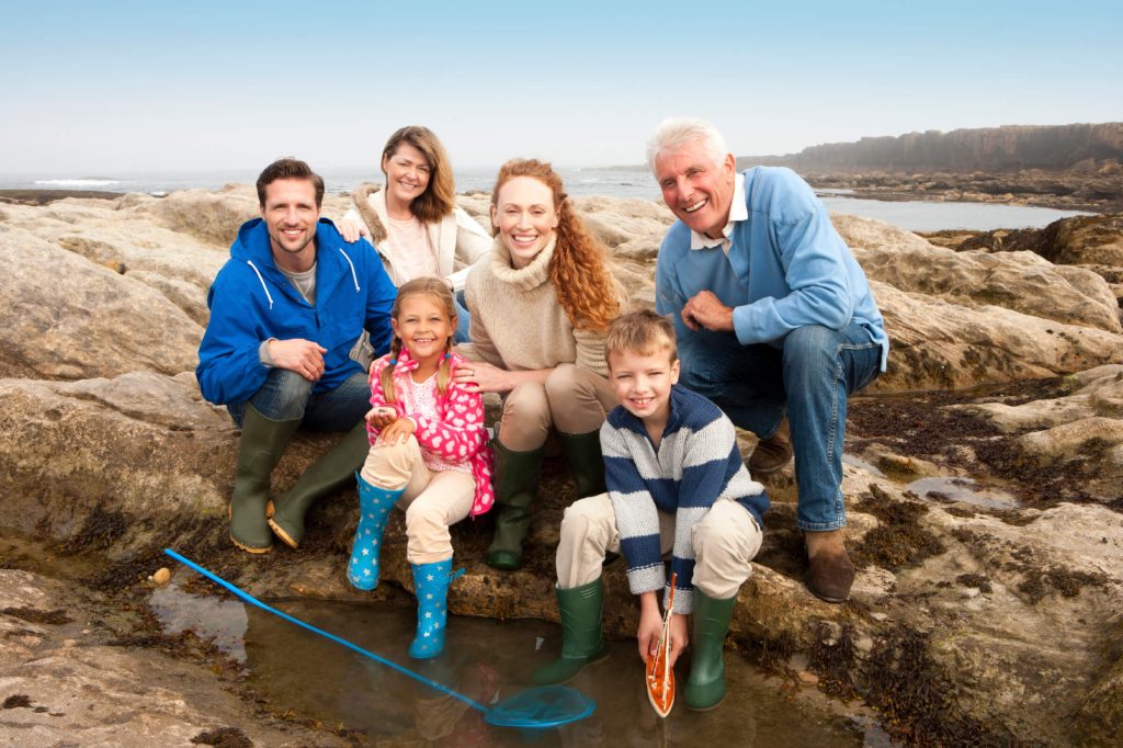 Family sitting together at a rocky beach